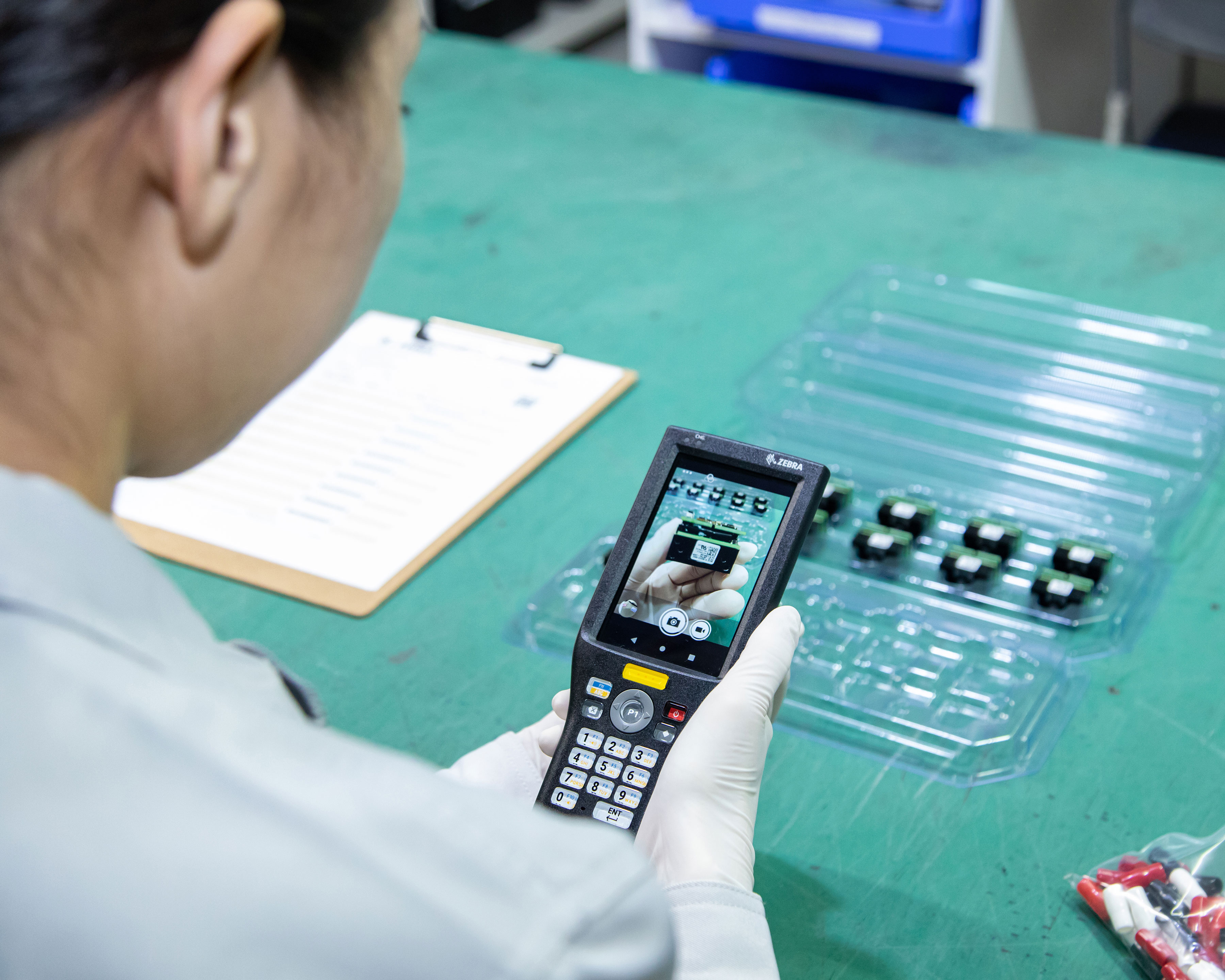 Manufacturing worker uses the camera of Zebra MC20 mobile computer to take pictures of a barcode labels on an electronic component