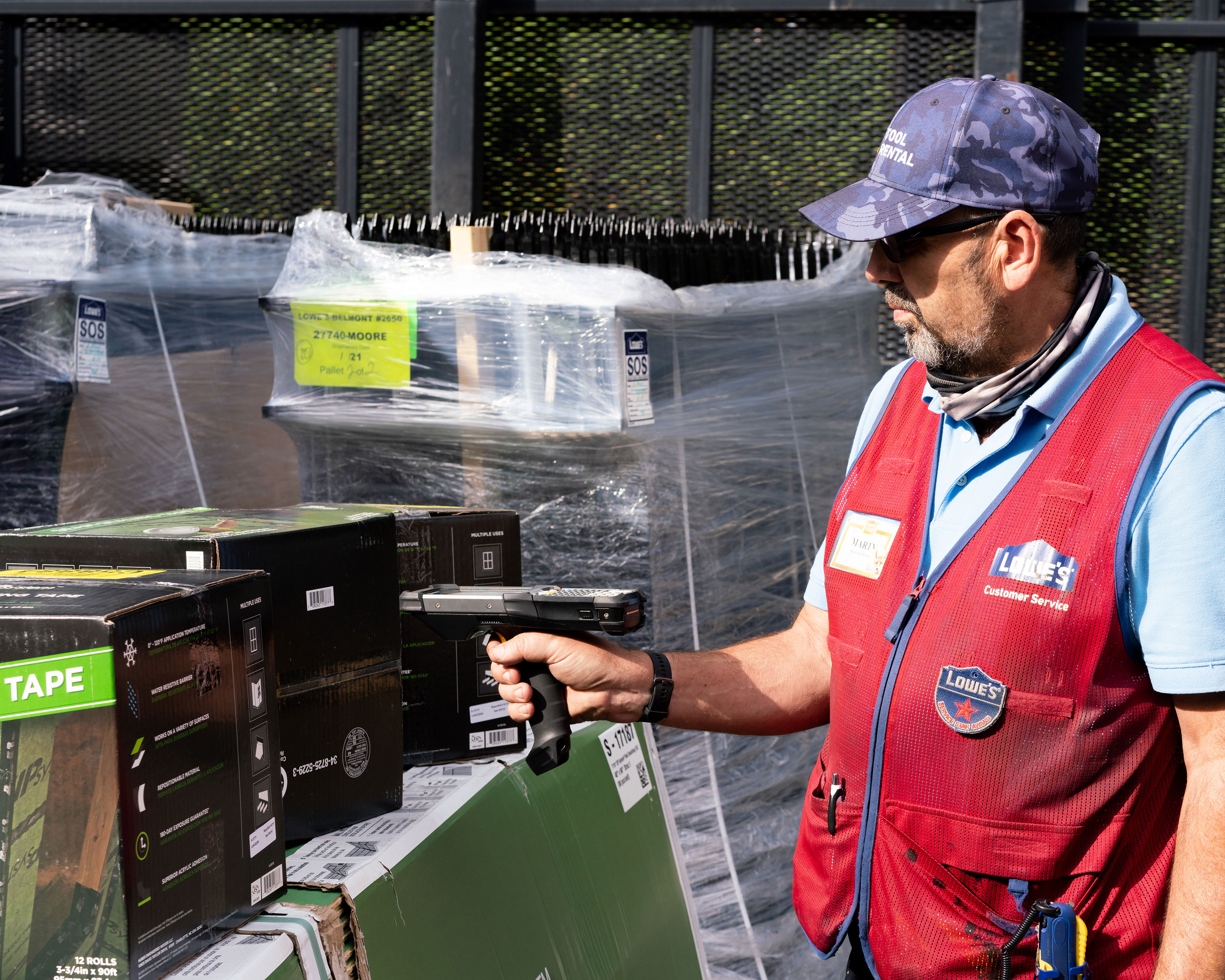 Retail worker uses Zebra MC9300 handheld computer to scan barcodes outdoors at a Lowe's Home Improvement store