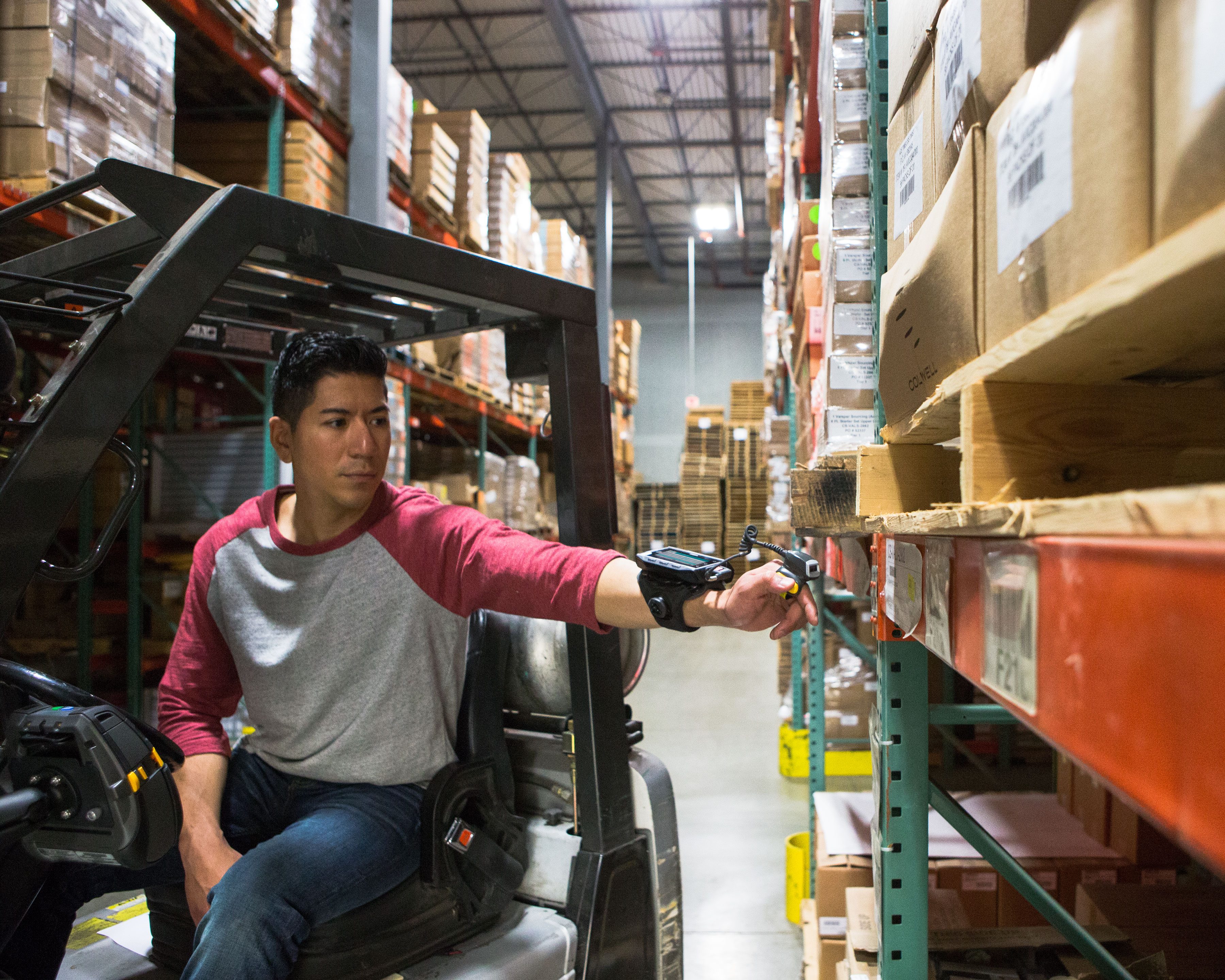 Warehouse worker uses Zebra RS5000 ring scanner to scan shelf barcodes while riding a forklift truck