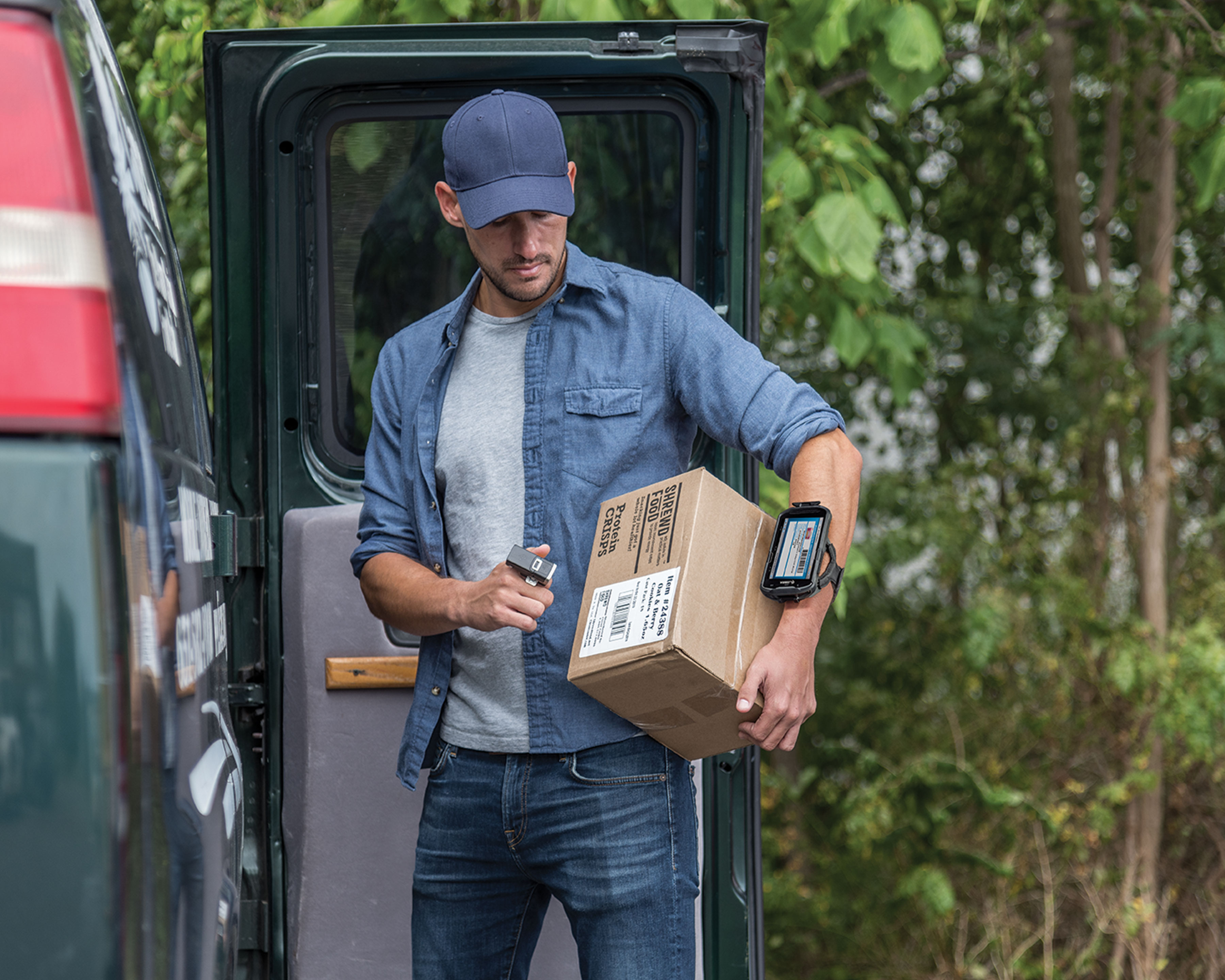 Worker holds a brown box while he scans its barcode label uses Zebra RS5100 wireless Bluetooth barcode scanner