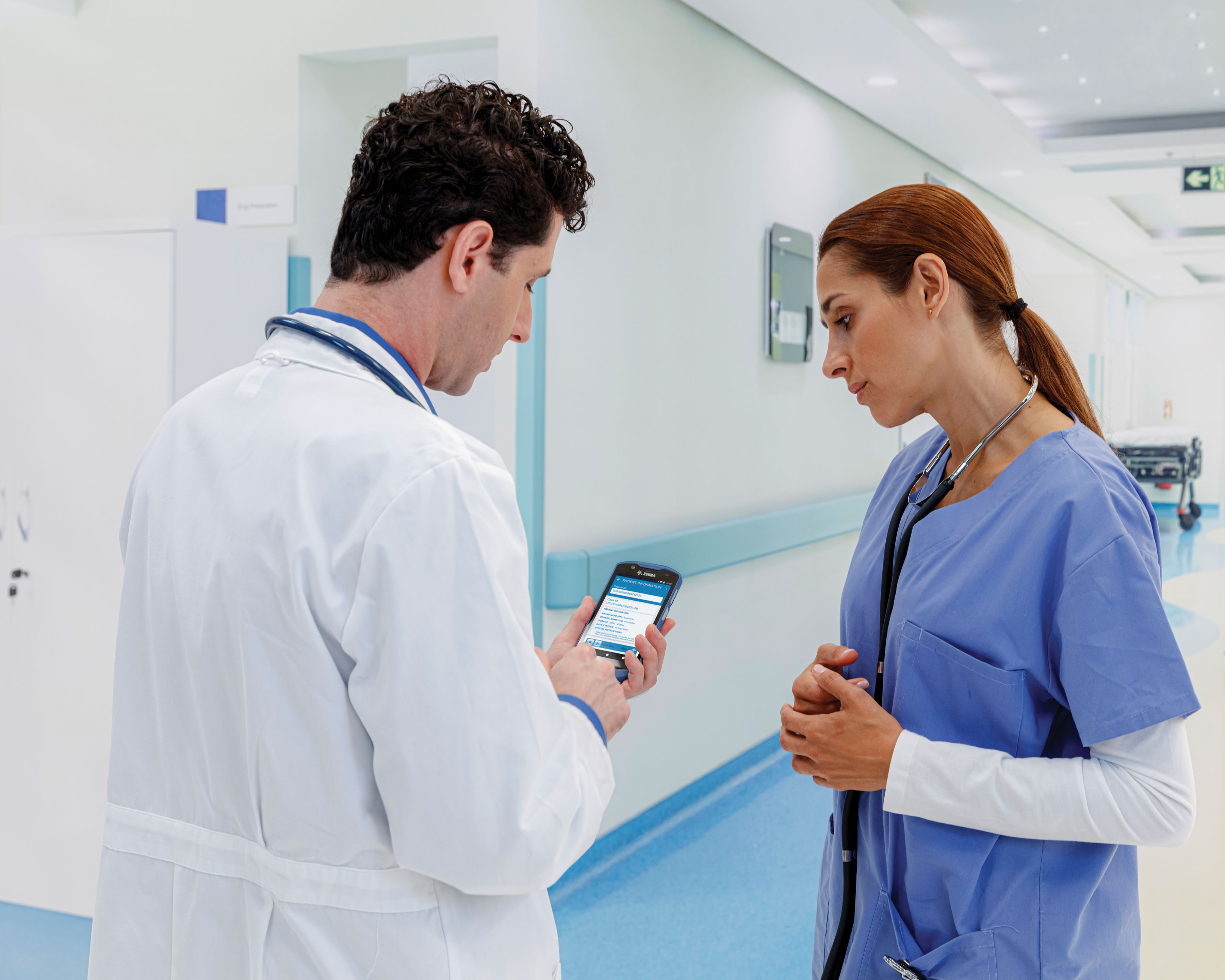 A doctor enters data on a Zebra TC5x mobile computer while a nurse looks at the device's screen