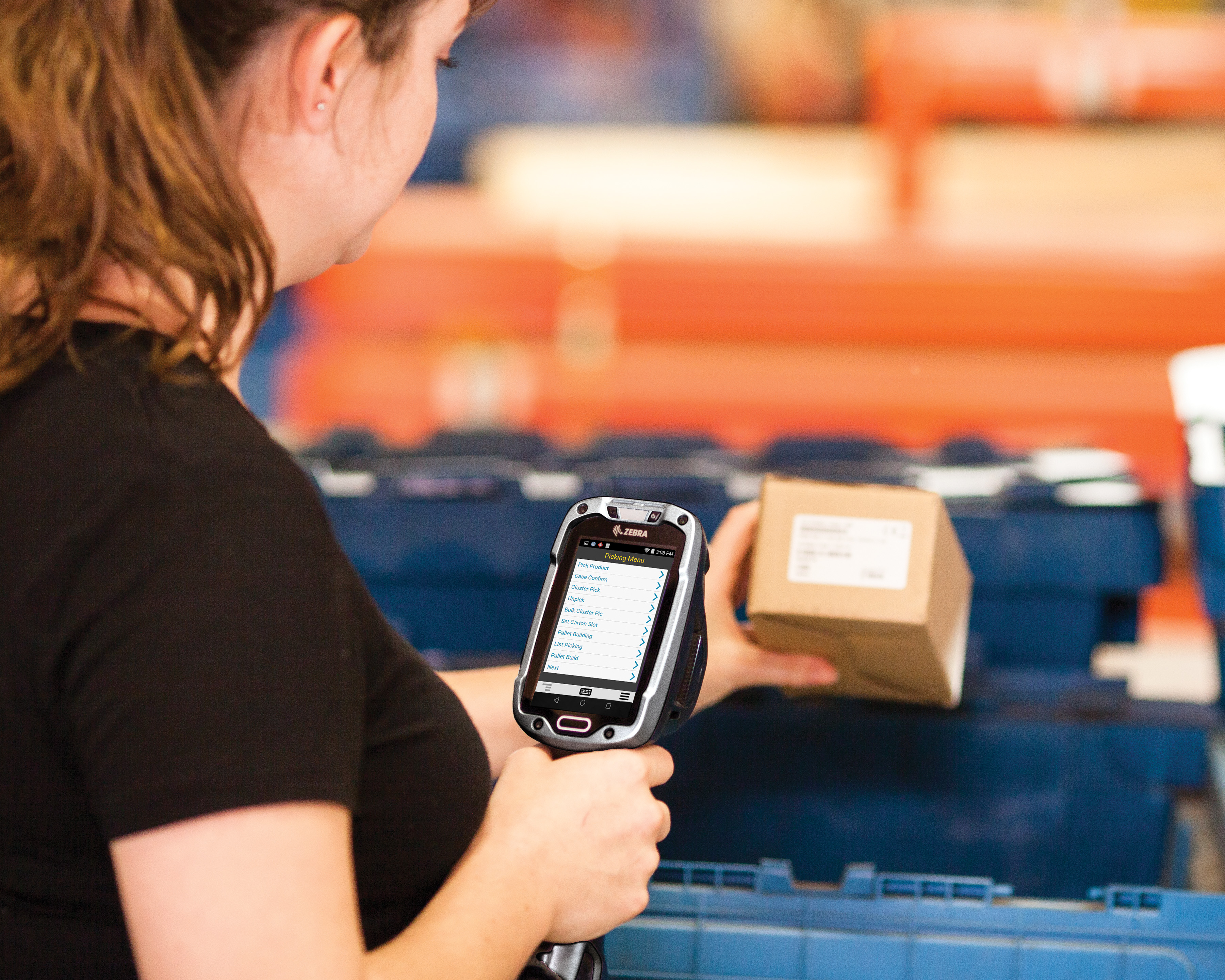 A woman holding a Zebra MC9300 handheld computer scanning a box