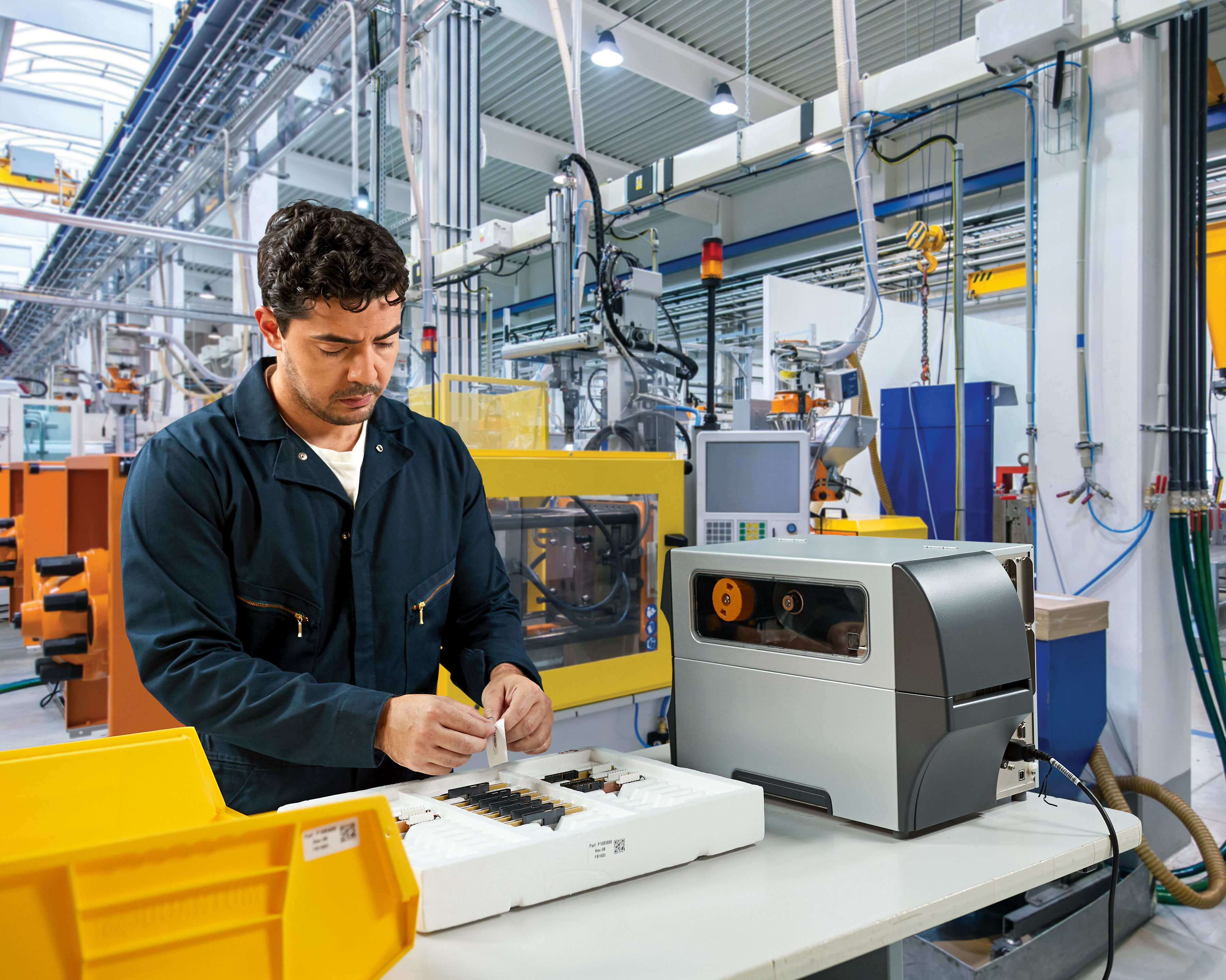 Zebra ZT400 industrial printer prints out sticker labels that worker uses to organize manufacturing electronic components