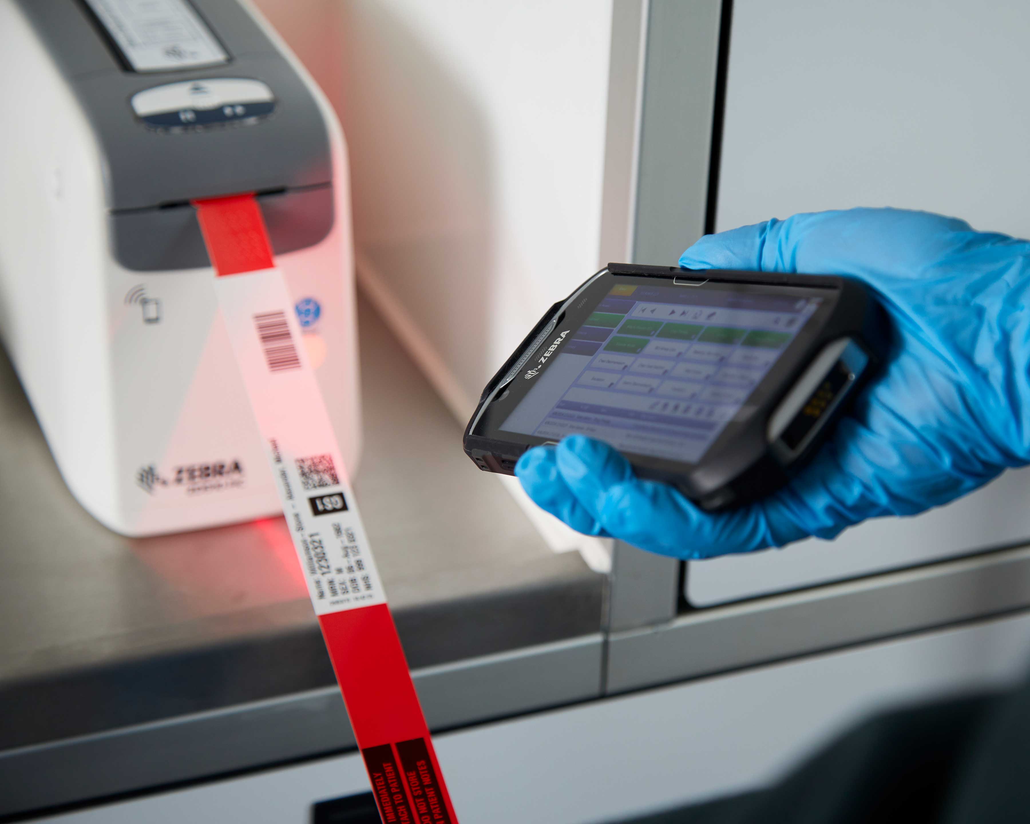 Gloved healthcare worker scanning a label out of a printer