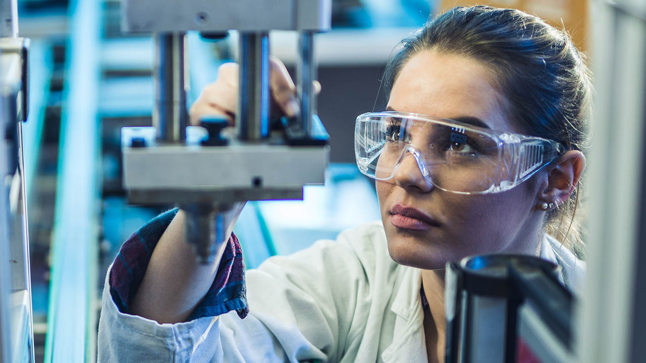 A woman inspects equipment on a manufacturing line