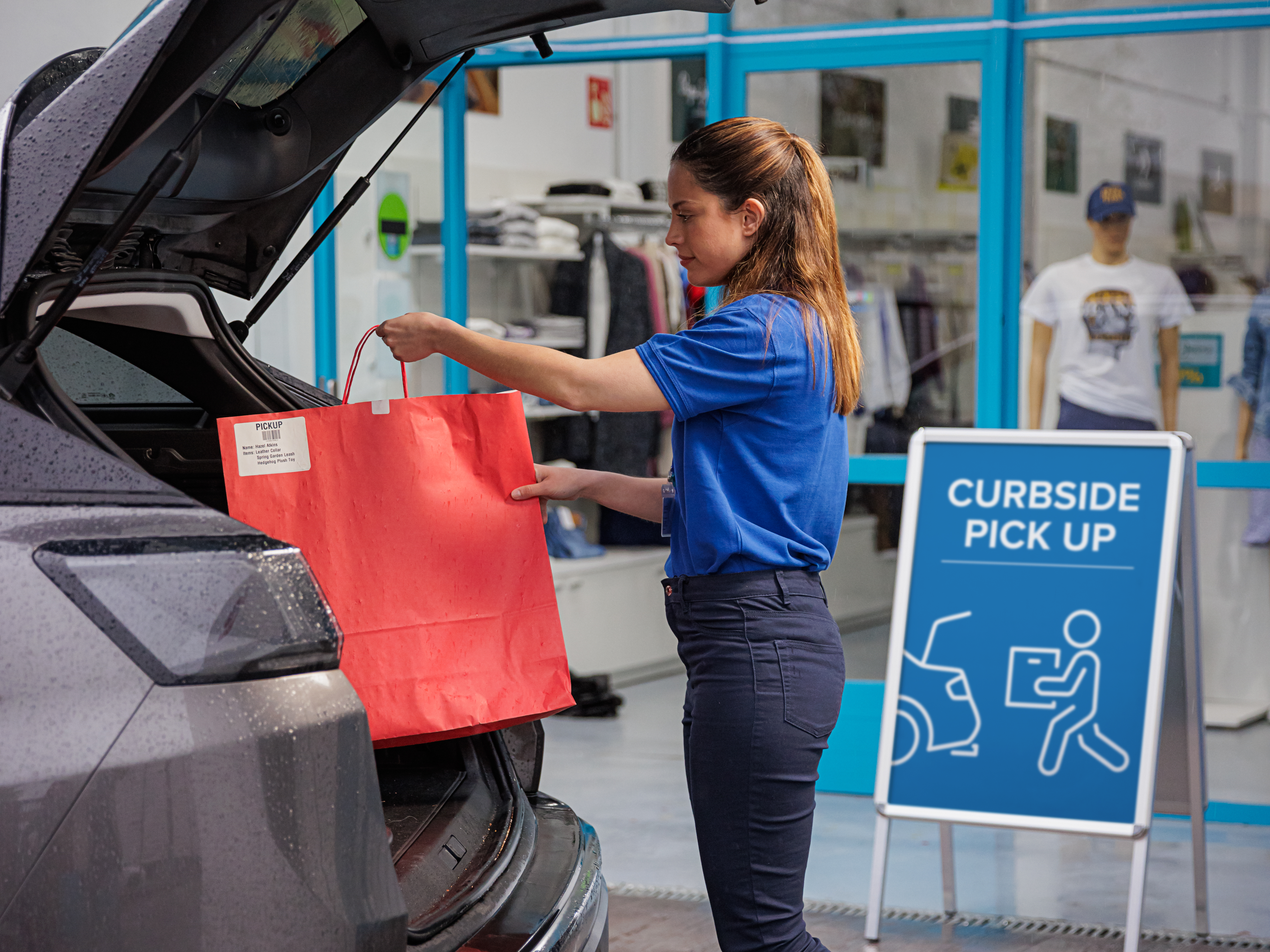 Sales associate loading bags into a customer's car at a curbside pick up