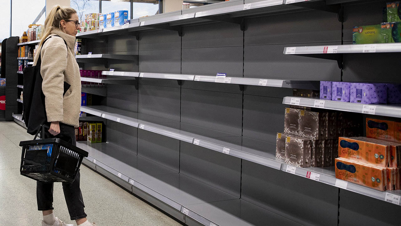 A woman looks at near-empty shelves at a grocery store