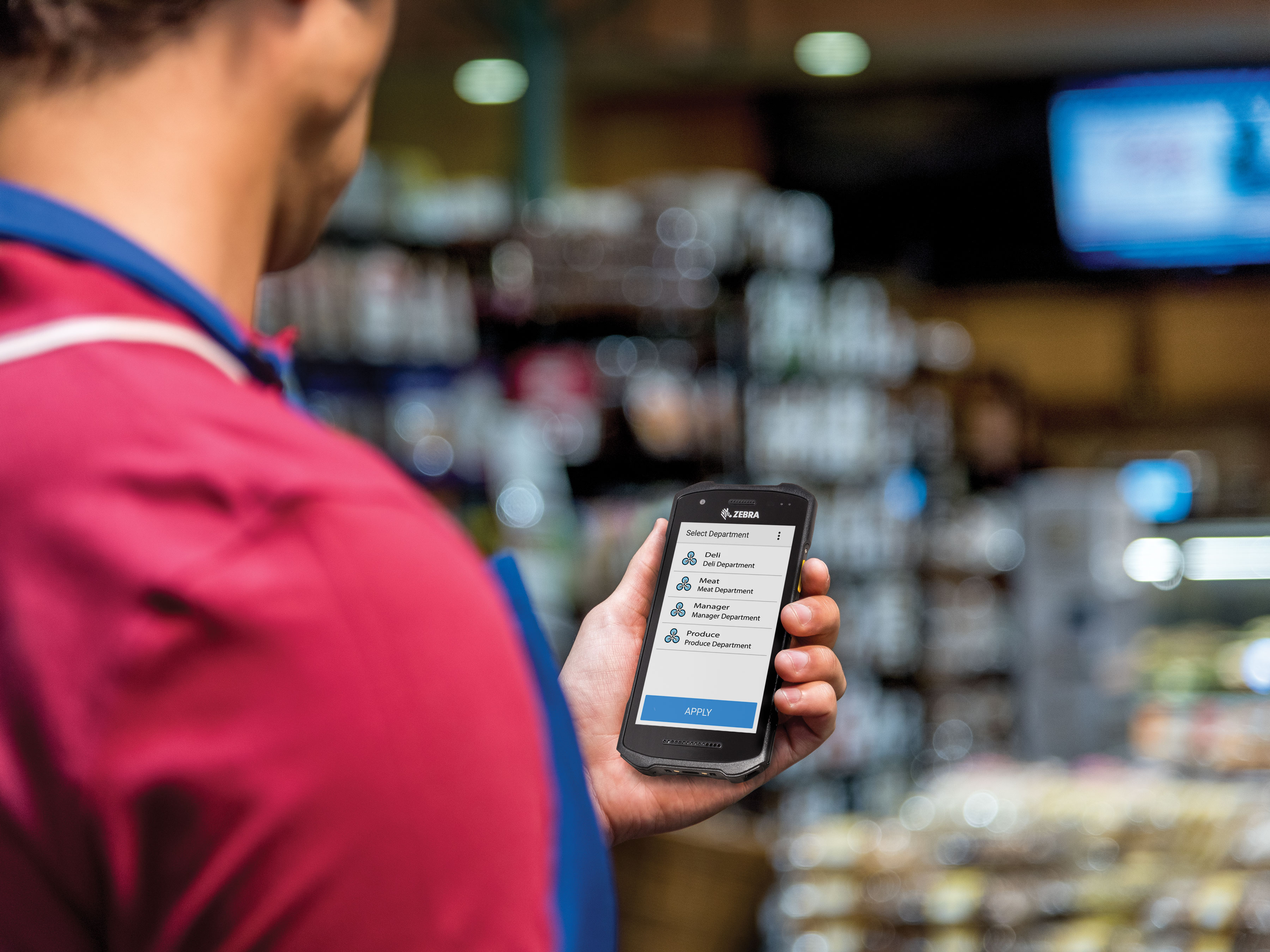 Grocery store worker holding a device