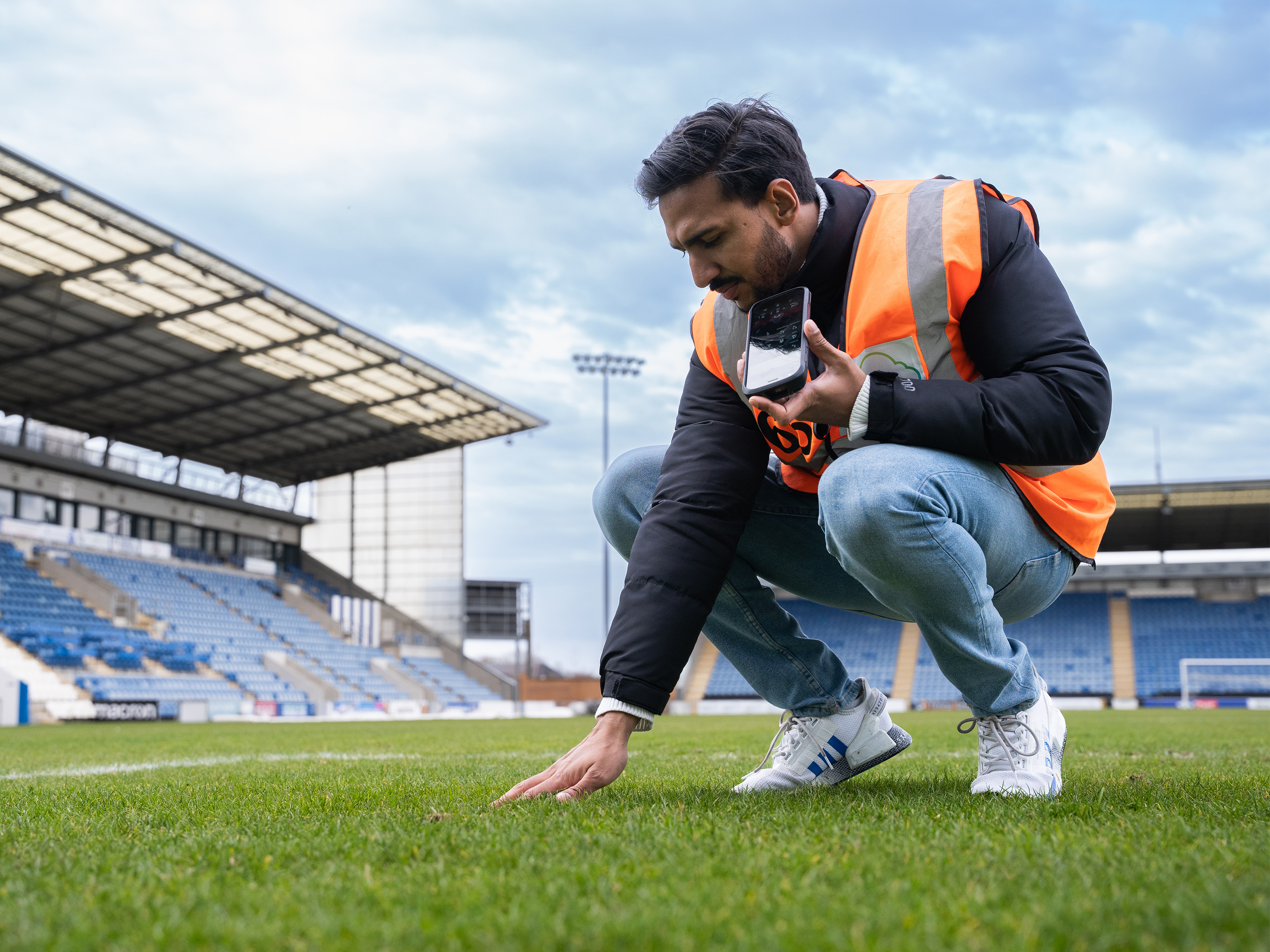 Man crouching on a football field touching turf