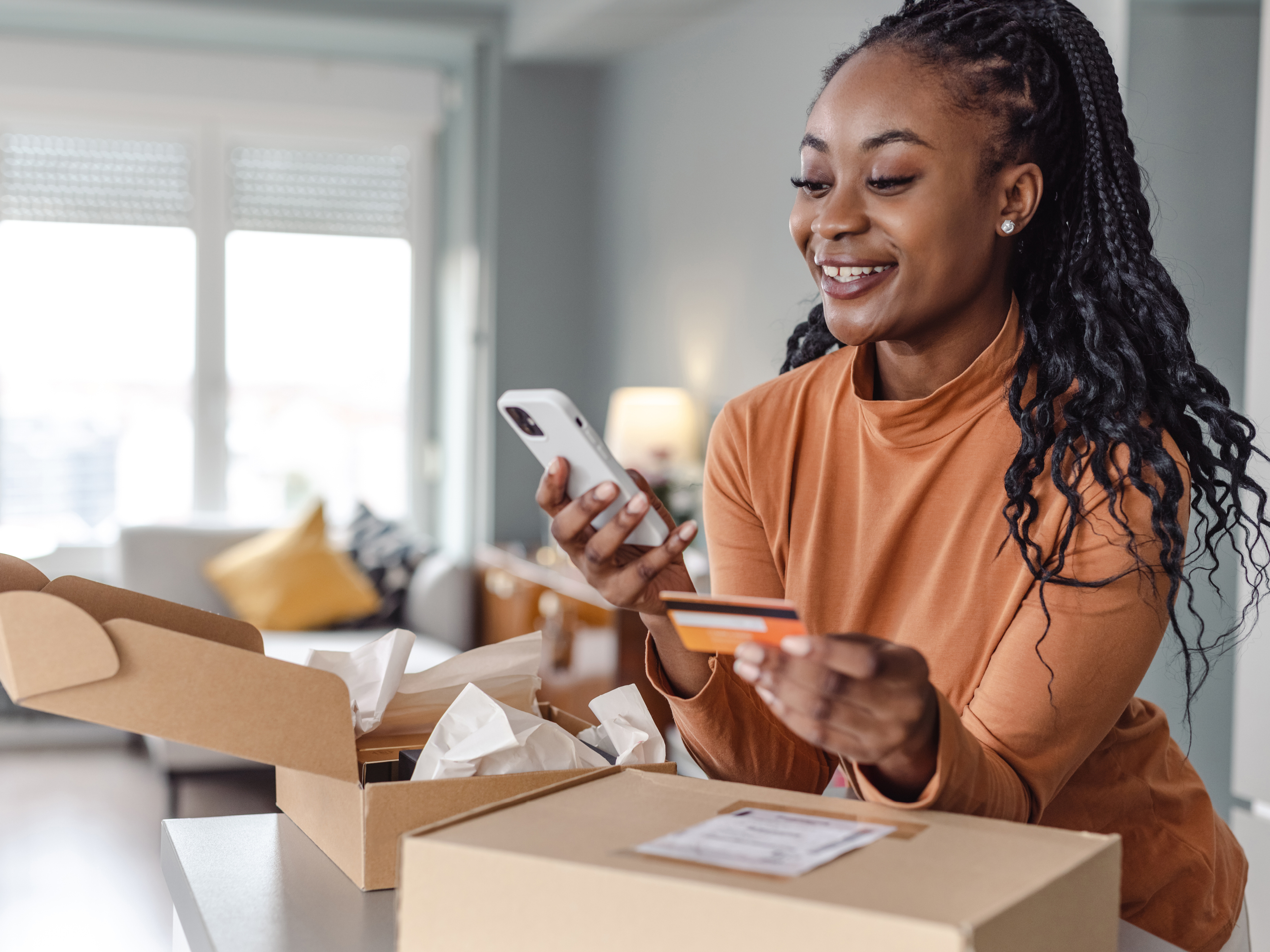 Woman holding smartphone and looking at her credit card