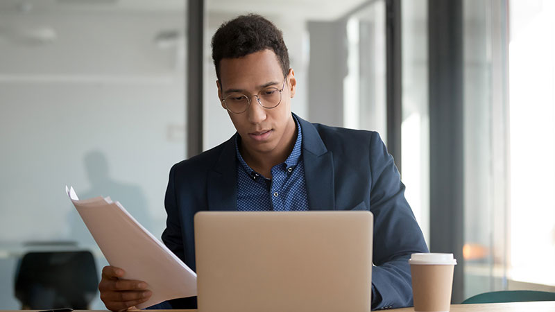 Banquero con traje y gafas trabajando en su computadora portátil