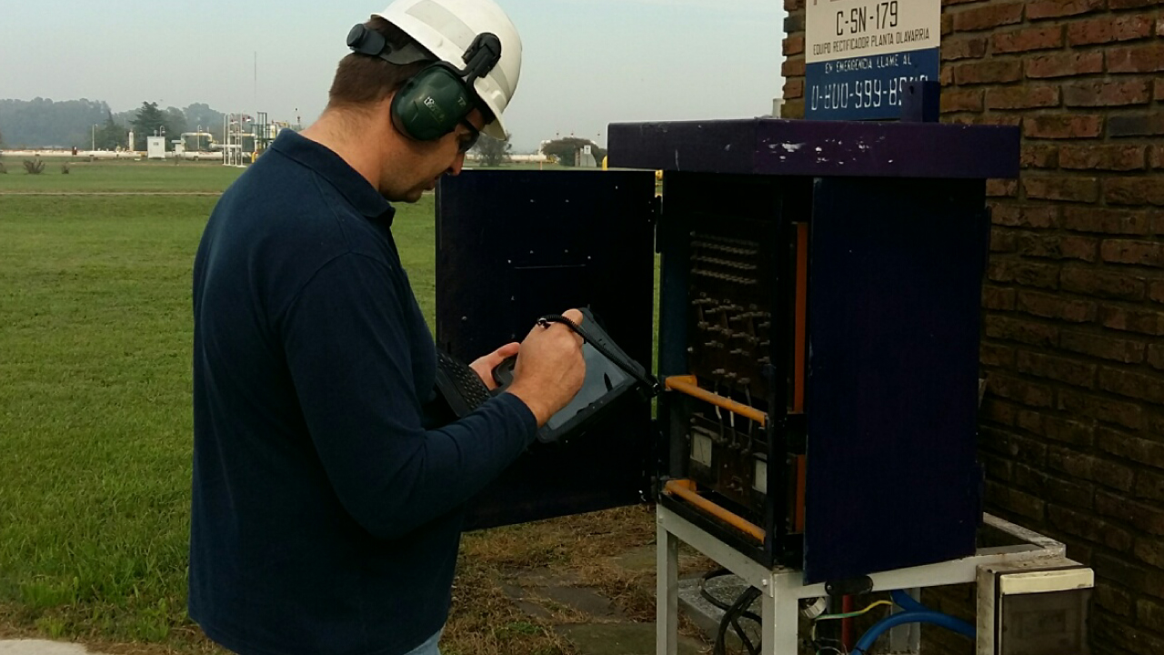 A TGS worker looks at a Zebra rugged tablet while servicing a piece of equipment in the field