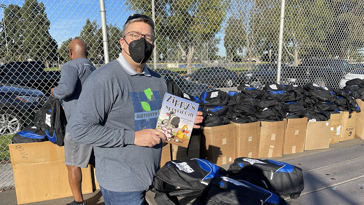 A volunteer at the 2022 Vincent Country Safe Zone Activity Day holds a "Zippy's Special Gift" book